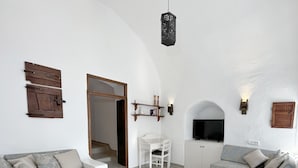 A modern living room with a white curved ceiling, a flat-screen TV, two sofas, a coffee table, and a wooden door.