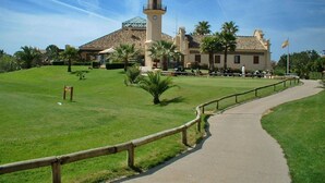 A historic building with a prominent tower, surrounded by a well-maintained lawn and a paved pathway. - SUN, NATURE AND BEACH. Cozy, bright, large garden with views of pine forests (Islantilla)