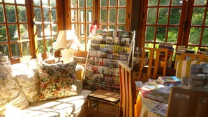 Rincón acogedor para leer con un banco acolchado, una mesita con libros y una ventana con vistas a la vegetación.