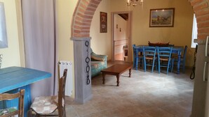 Un área de comedor con una mesa y sillas azules, un banco de madera y un piso de baldosas.