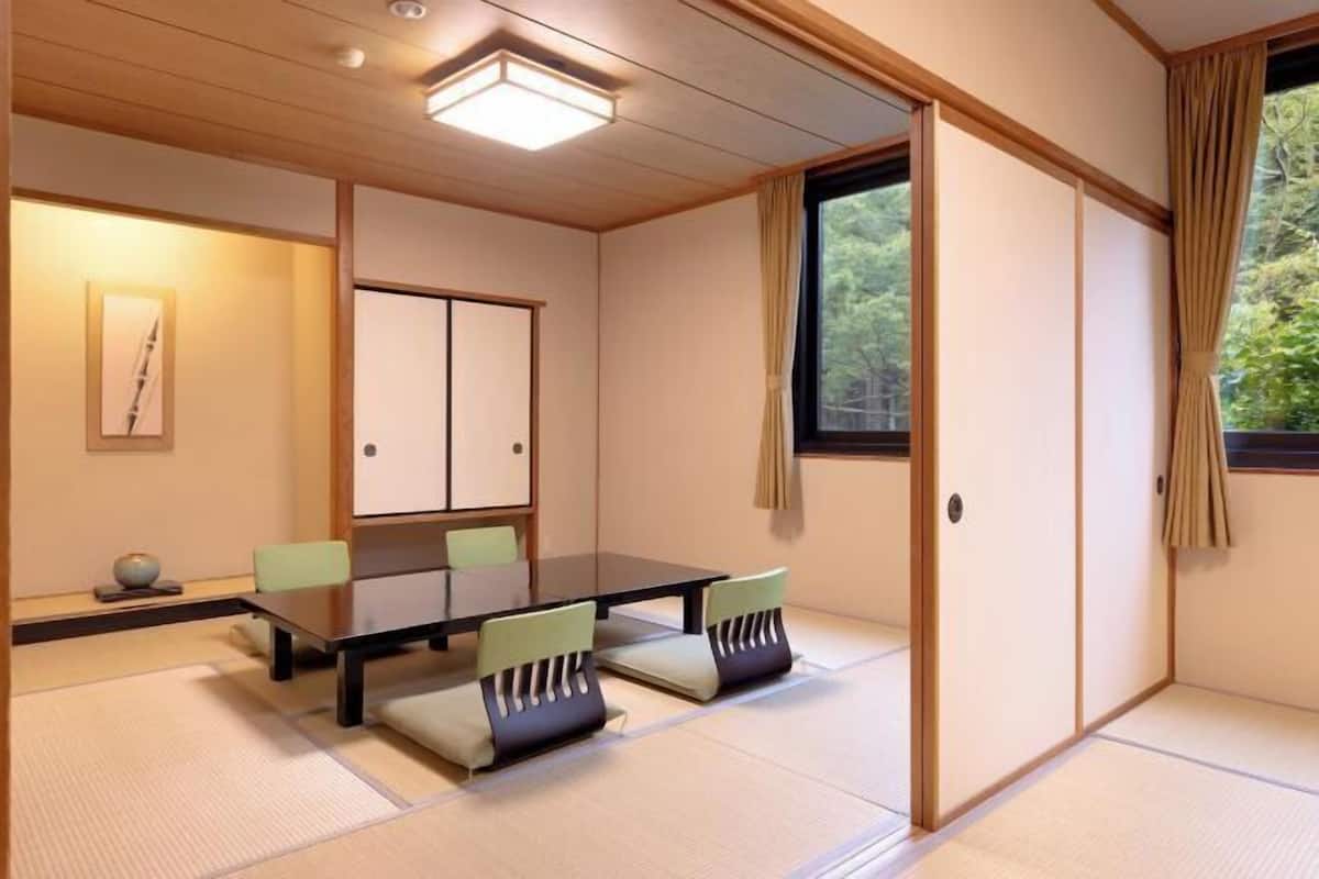 Una habitació japonesa tradicional amb tatami, una taula baixa i cadires amb coixins verds.