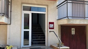 Entrada de un edificio con una escalera que conduce a un piso superior, un detector de incendios y una entrada con portón.