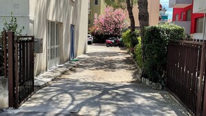 Una calle urbana estrecha con acera, coches estacionados y edificios residenciales.