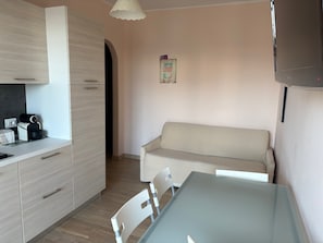 Een compacte woonruimte met een kitchenette, een bank en een eettafel.