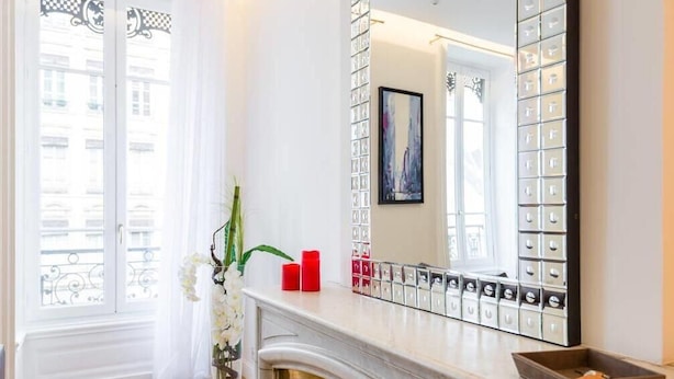 A modern bathroom with a large mirror, a fireplace, and a view of the city through the window. - Exceptional 2-bedroom apartment 74m2 Place Bellecour (Downtown) (Lyon)