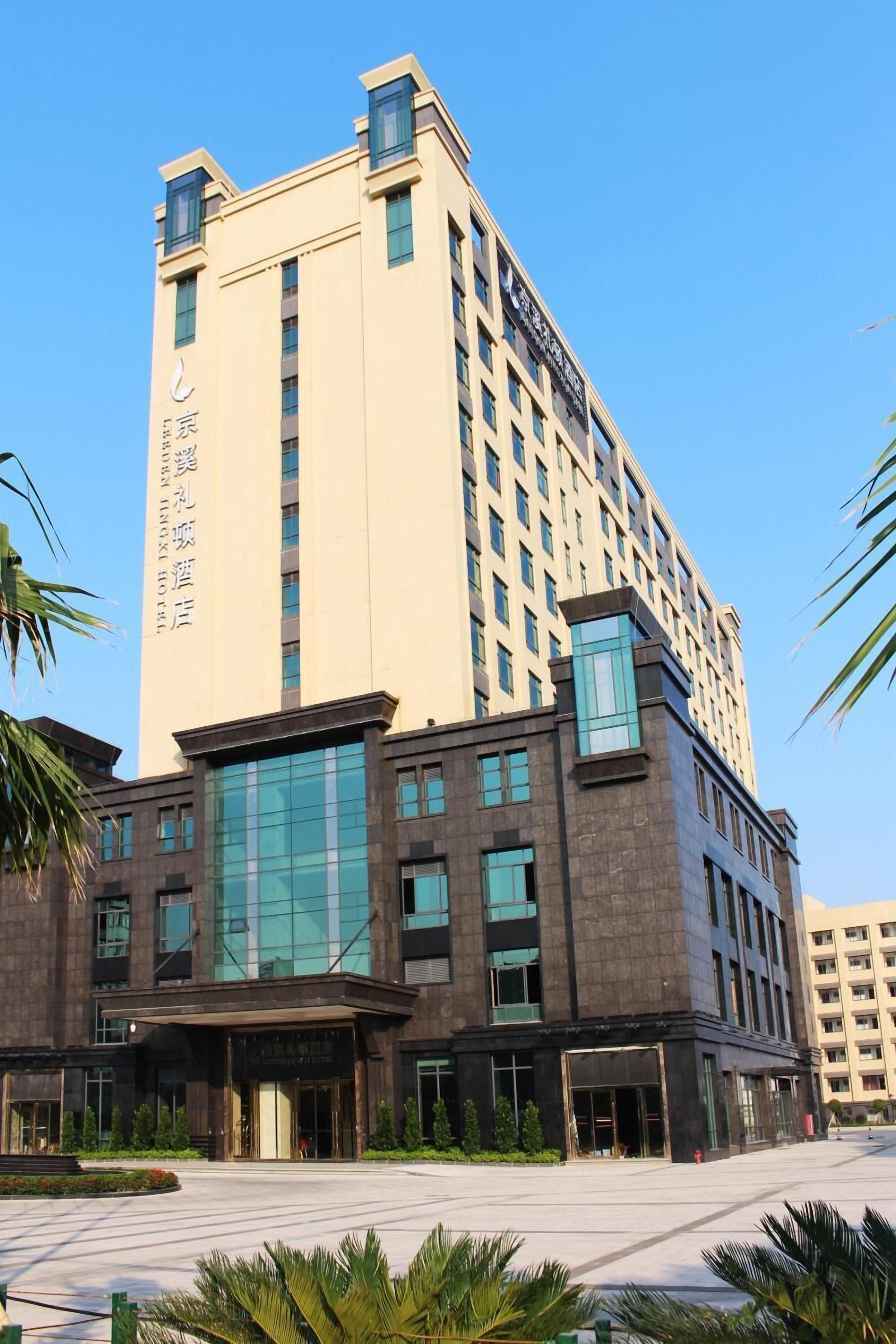 Un hotel de varios pisos con una entrada destacada, ventanas amplias y un cielo despejado.