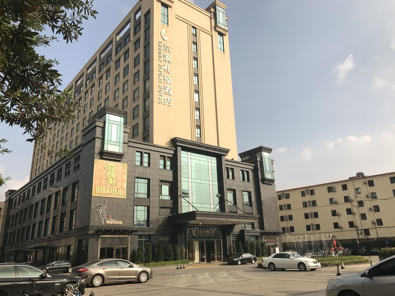 A multi-story hotel with a prominent entrance, large windows, and a sign indicating it is a hotel.