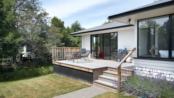A modern house with a deck, outdoor seating, and a garden.