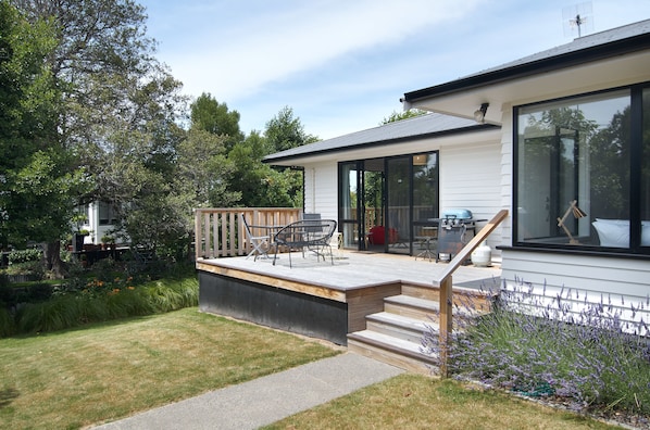 A modern house with a deck, outdoor seating, and a garden. - Brookside Villa (Christchurch)