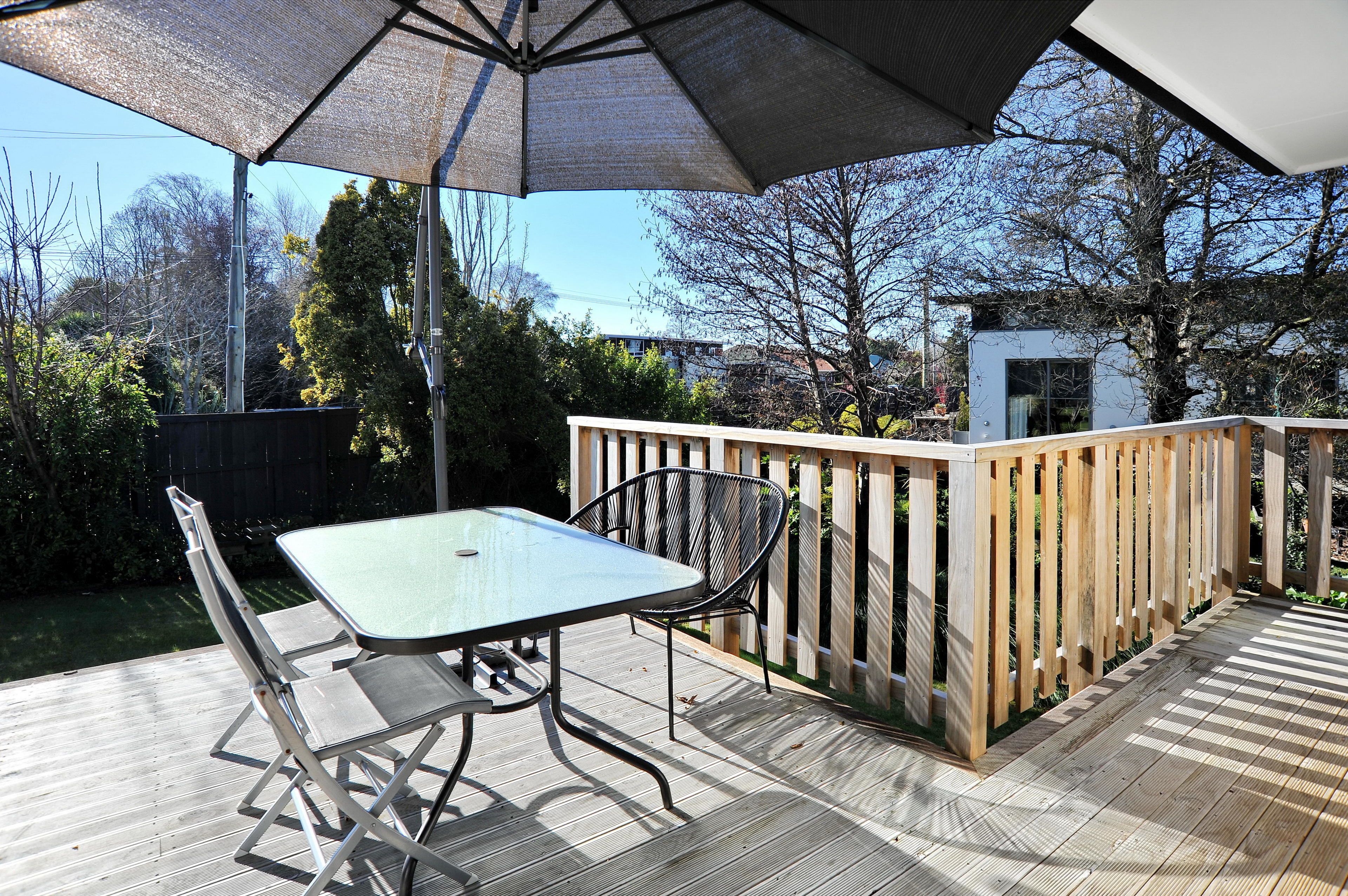 An outdoor patio with a table and chairs, a wooden deck, and a view of the surrounding area.