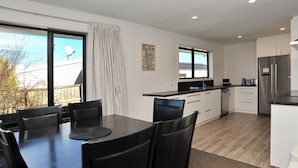 A modern kitchen with a large island, white cabinets, and a stainless steel refrigerator. - Brookside Villa (Christchurch)