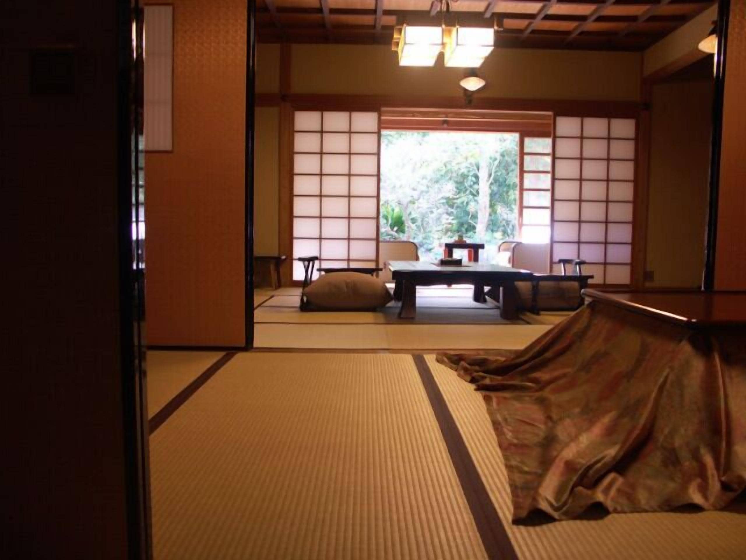 A traditional Japanese room with tatami flooring, a low table with cushions, and sliding shoji doors.