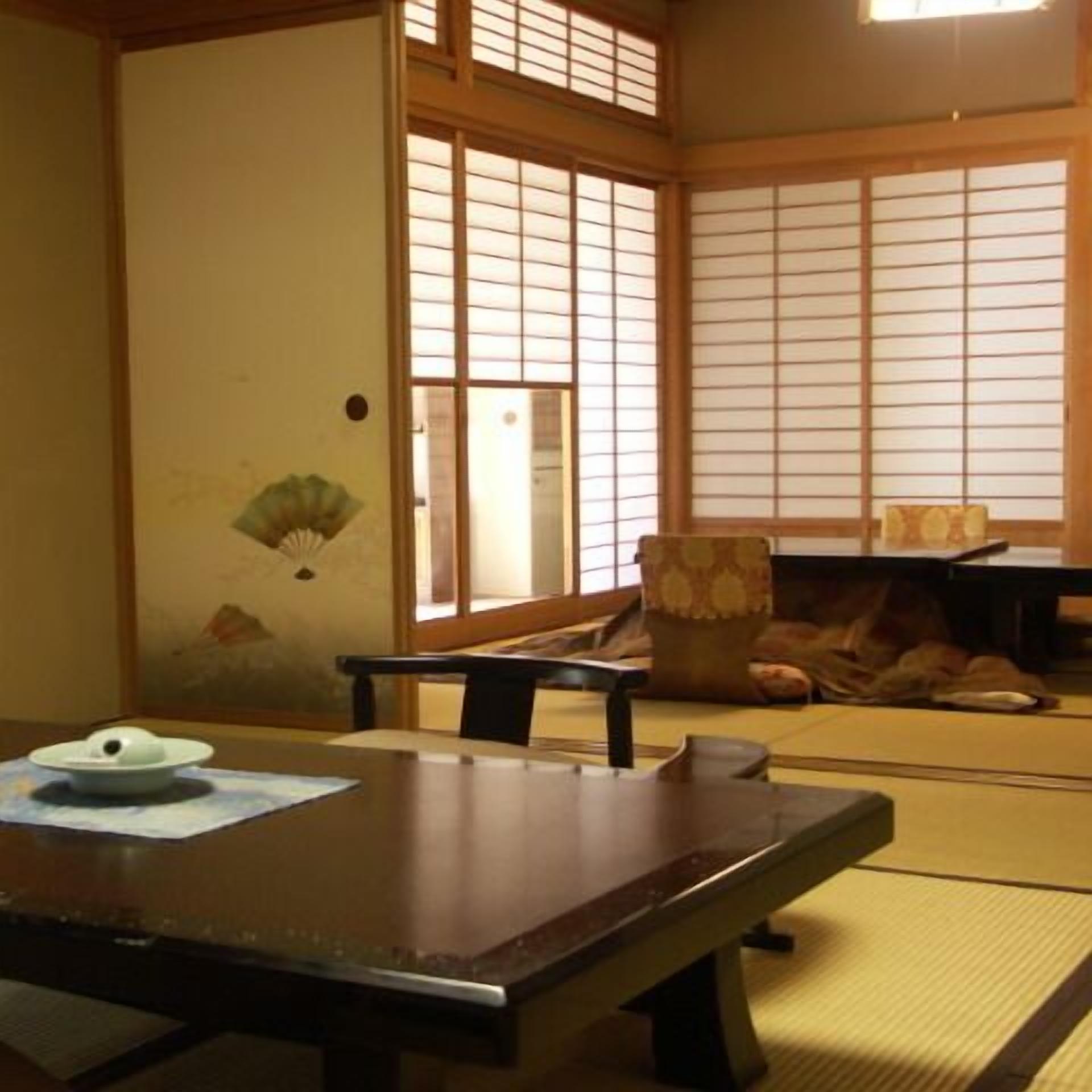 Een traditionele Japanse kamer met tatami vloerbedekking, een lage tafel, een stoel en schuifdeuren van shoji-papier.