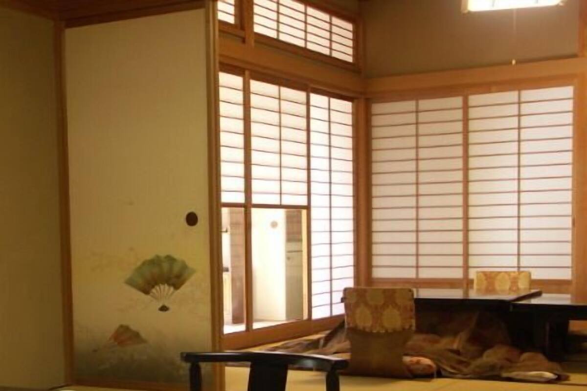 Ein traditioneller japanischer Raum mit Tatami-Bodenbelag, einem niedrigen Tisch, einem Stuhl und verschiebbaren Shoji-Türen.