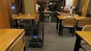 Een restaurant met houten tafels en stoelen, een centrale koffiemachine en uitzicht op de straat.