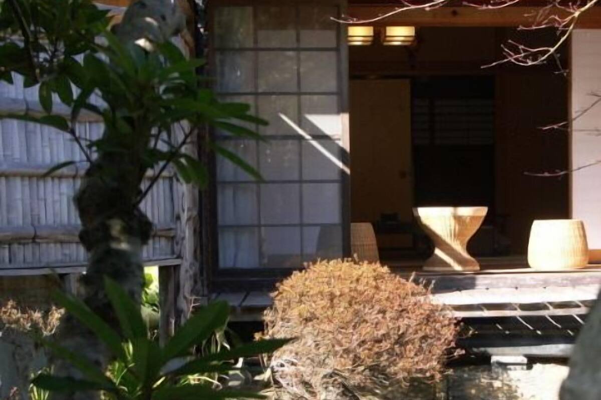 Ein Teich mit Koi-Karpfen, eine Holzkonstruktion und ein traditionelles japanisches Gebäude im Hintergrund.