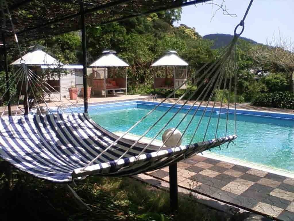 Una hamaca junto a una piscina con sombrillas y vistas a la montaña.