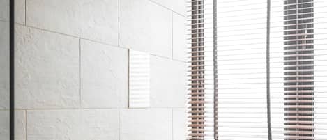 A bathroom with a bathtub, a shower, and a window with blinds.