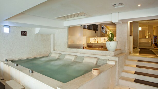 Een wellnessruimte met een ruime hottub, een gezellig zitgedeelte en een trap naar een hoger niveau.