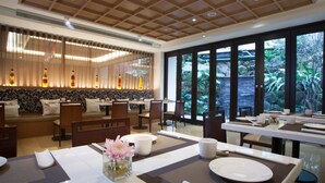 Een moderne eetruimte met gedekte tafels, een bar met flessen en grote ramen met uitzicht op het buitengebied.