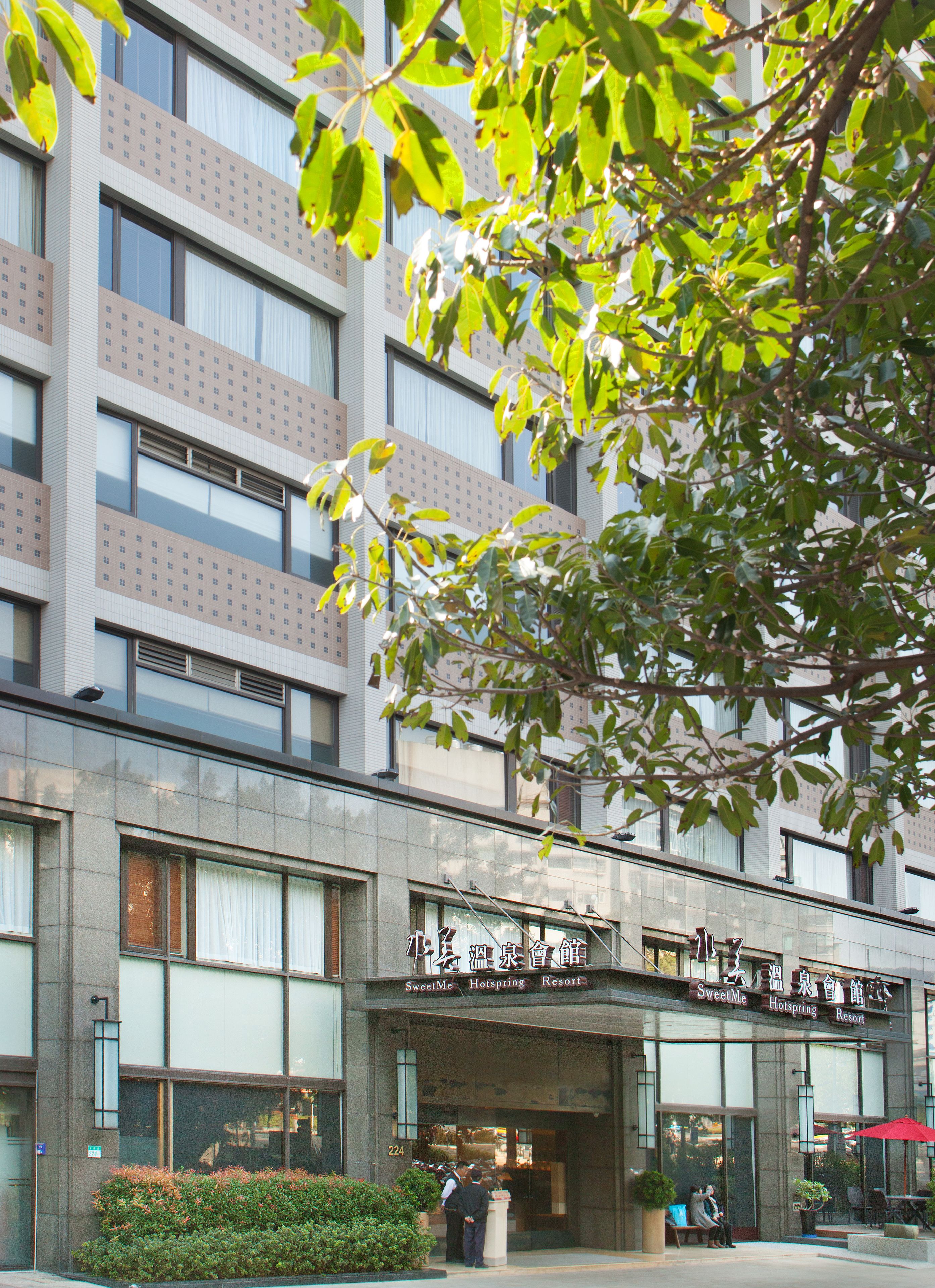 A hotel with a modern facade, large windows, and a sign indicating it is a SweetMe HotSpring Resort.