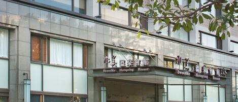 A hotel with a modern facade, large windows, and a sign indicating it is a SweetMe HotSpring Resort.