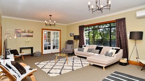 A living room with a sofa, armchairs, a coffee table, and a rug. - Racecourse Villa (Christchurch)