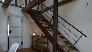 A wooden staircase with metal railings leading to an upper level. A small table with two lanterns is placed near the staircase. - Old renovated farmhouse, ca.1840, high quality furnishings with Bodden view (Ummanz)