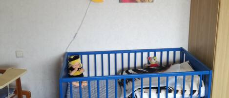 En rejse seng med legetøj, et ur og to Winnie the Pooh plakater på væggen.