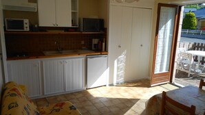 A compact kitchen with white cabinets, a microwave, and a coffee maker. There is a small dining area with a table and chairs.