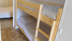 A bunk bed room with a window, wooden walls, and a tiled floor.