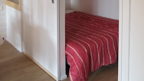 Ein kleiner Raum mit einem Bett, einer Schiebetür und einem Fenster.