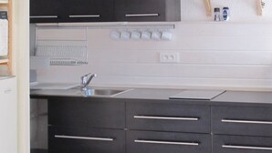 Eine moderne Küche mit dunklen Schränken, einer Edelstahlspüle und einer weißen Arbeitsplatte.