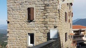 Un bâtiment en pierre doté d’un toit en pente, de nombreuses fenêtres avec volets et d’une enseigne indiquant qu’il s’agit d’un restaurant.