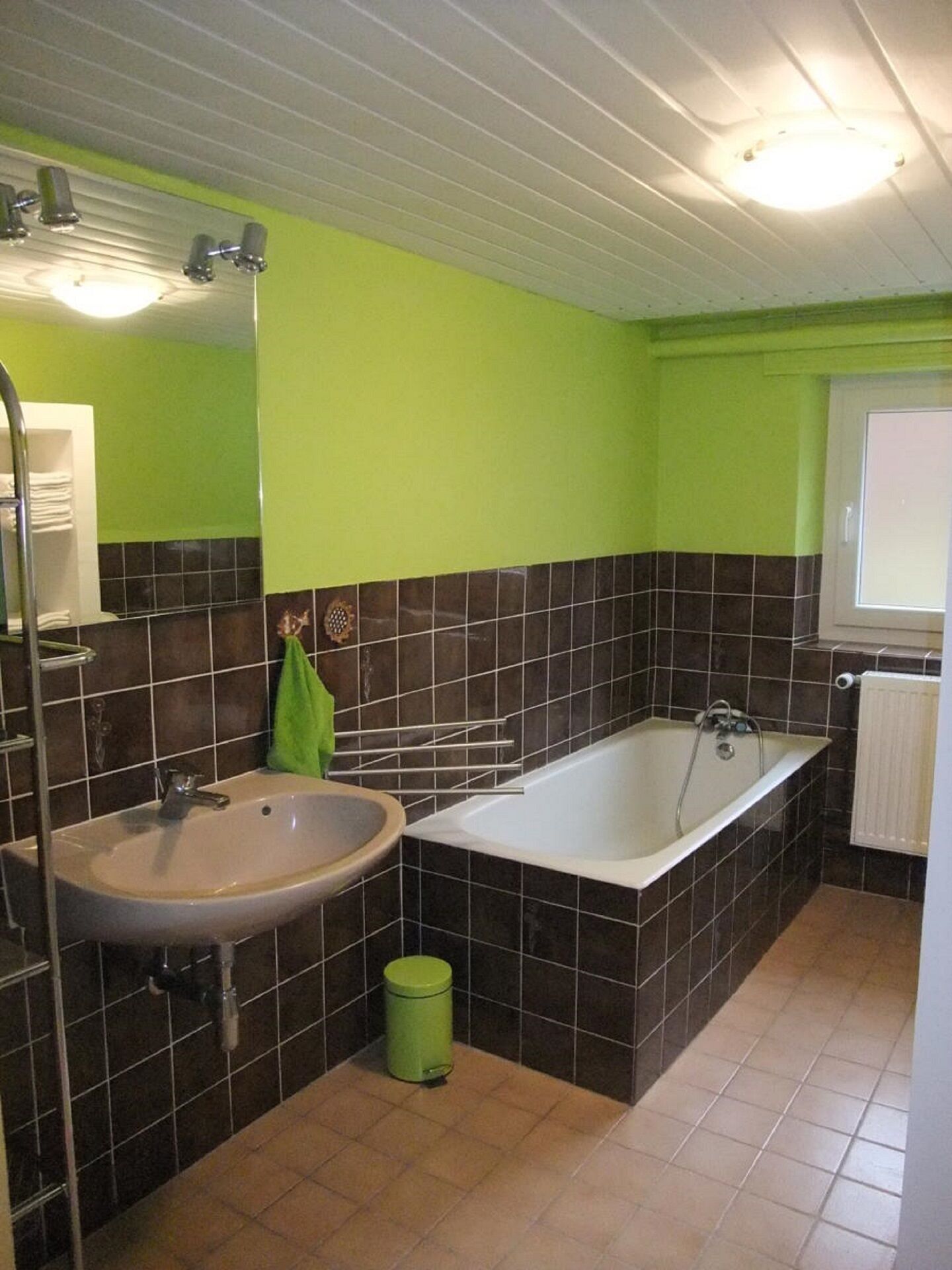 A bathroom with a sink, bathtub, and green walls.