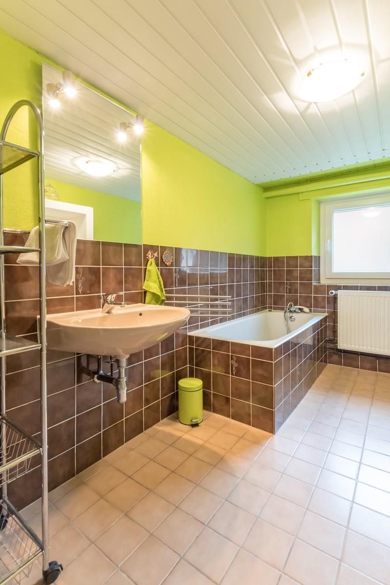 A bathroom with a sink, bathtub, and a mirror.