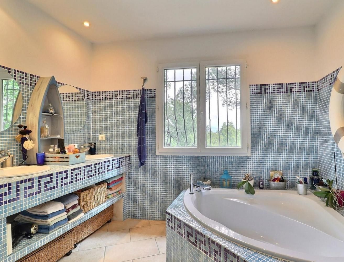 Une salle de bain avec une baignoire sur pieds, un grand miroir et une fenêtre.