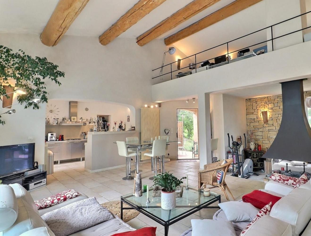 A spacious living area with a glass coffee table, a sofa, and a dining area with a kitchen in the background.