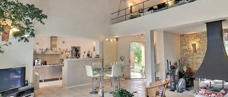 A spacious living area with a glass coffee table, a sofa, and a dining area with a kitchen in the background.