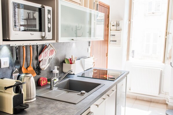 Une cuisine moderne équipée d’un four à micro-ondes encastré, d’une grande fenêtre et d’un évier.