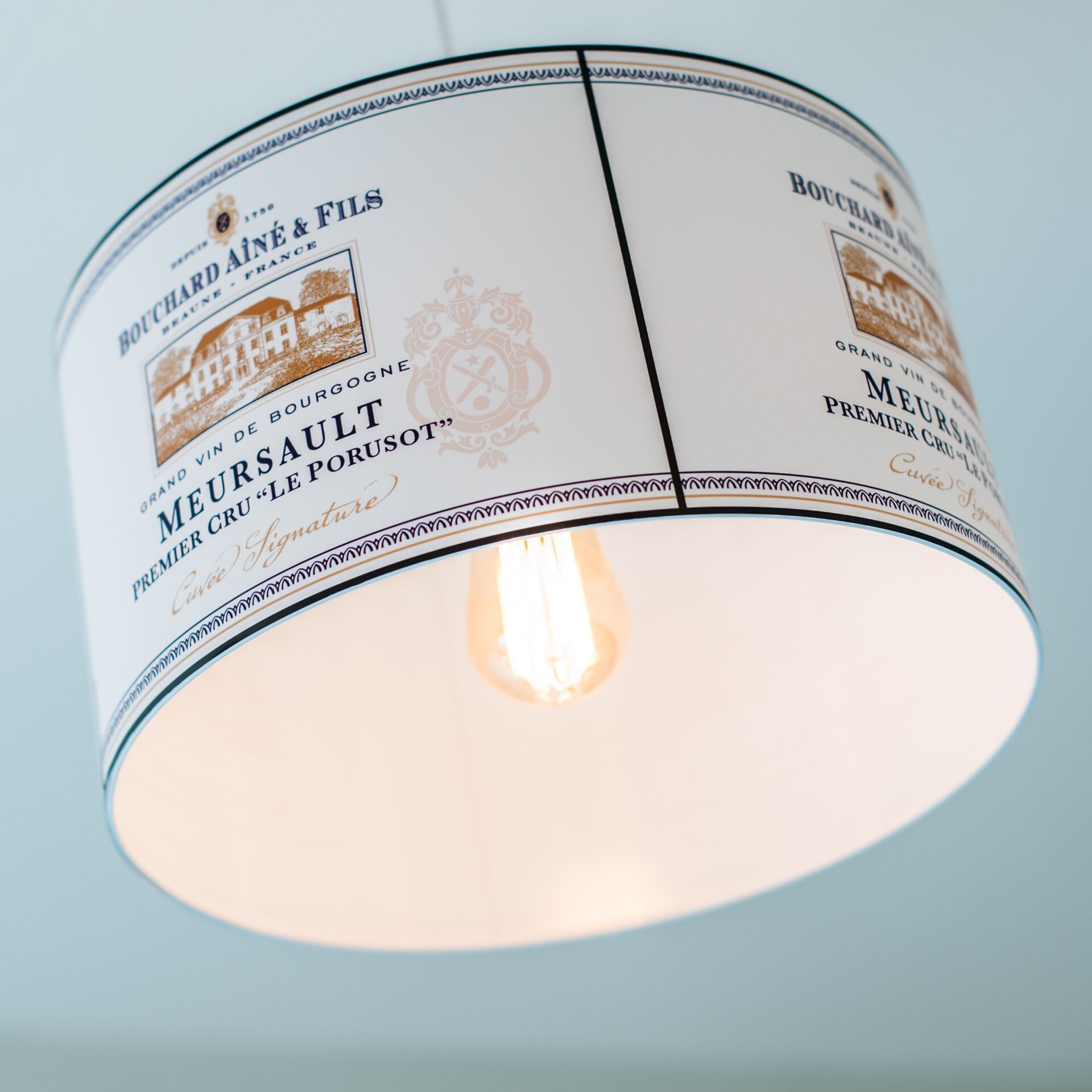 A cylindrical light fixture with a label that reads "Bouchard & Fils" and "Meursault Premier Cru 'Le Porusot'".