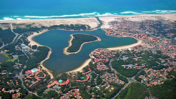 An aerial view of a coastal resort with a large central lagoon, surrounding residential areas, and a beach. - PROMO ☀️☀️☀️ LES VILLAS DU LAC, swimming pool, tennis, petanque, mini golf (Soustons)