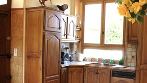 Una cocina con armarios de madera, una mesa de comedor con sillas, un ventanal con vistas a zonas verdes y una figura decorativa de un caballo en la pared.