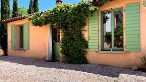 A house with green shutters, a small porch, and a gravel driveway. - Quiet Salagou cottage with lovely view over the valley (Octon)