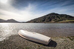 A boat on a pebbly shore with a lake and mountains in the background.