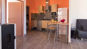 A compact kitchen with modern appliances, a dining area with a table and bar stools, and a sofa in the adjacent living area. - Quiet Salagou cottage with lovely view over the valley (Octon)