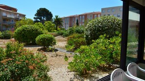A view of a courtyard with various plants and a pathway, surrounded by buildings with balconies. - Quiet air-conditioned apartment 10 minutes' walk from the beaches and shops (Bormes-Les-Mimosas)