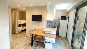 A compact kitchen with a wooden table, a microwave, and a refrigerator. - Quiet air-conditioned apartment 10 minutes' walk from the beaches and shops (Bormes-Les-Mimosas)