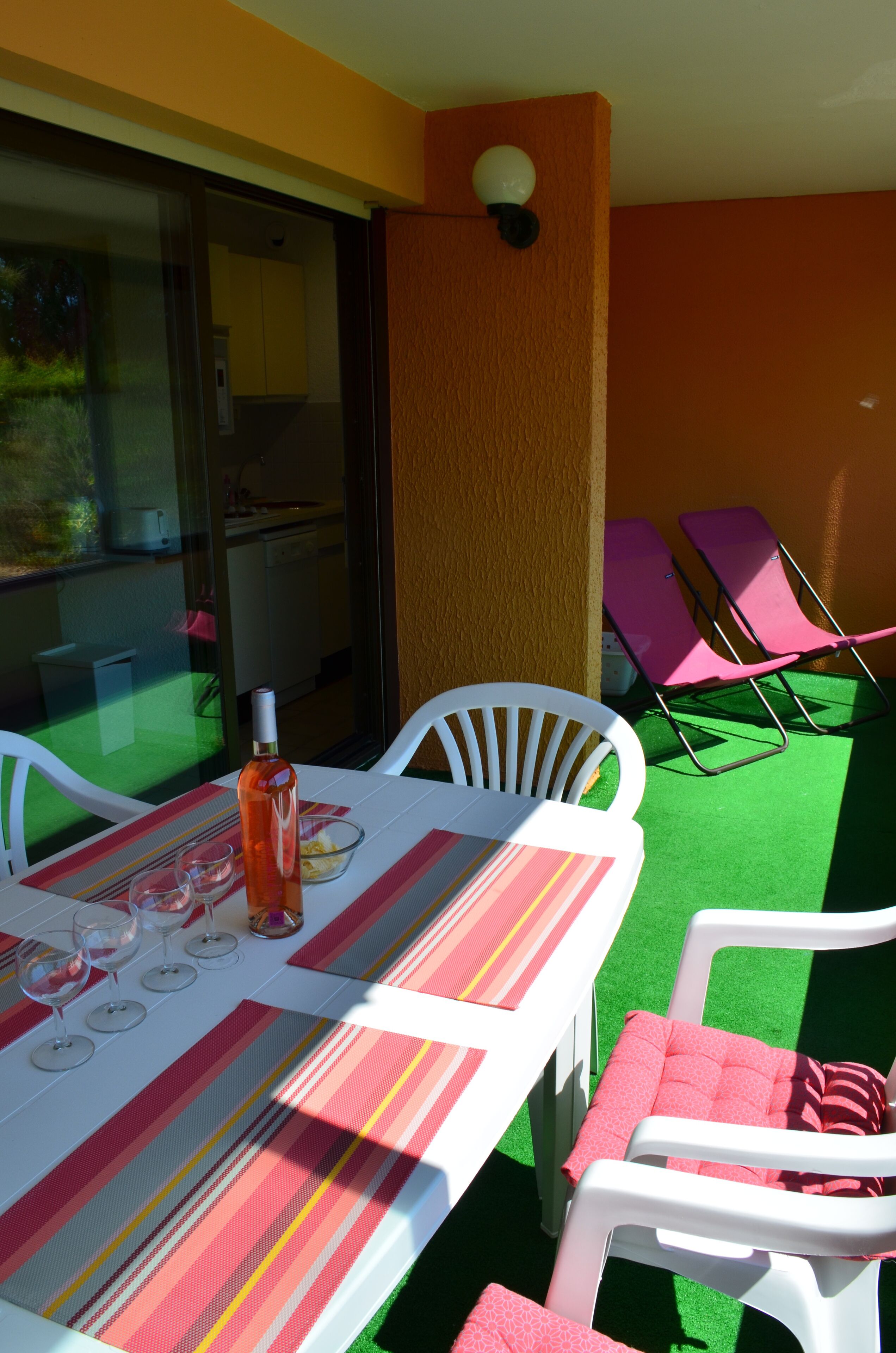 Un coin repas avec une table dressée pour quatre personnes, des chaises et une bouteille de vin.
