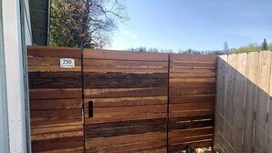 Une porte en bois avec un panneau indiquant un numéro, un chemin en béton et une zone recouverte de gravier.